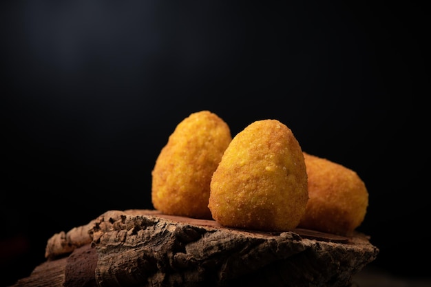 Arancini rice balls Fried rice balls in paper on brown wooden background Snack street food