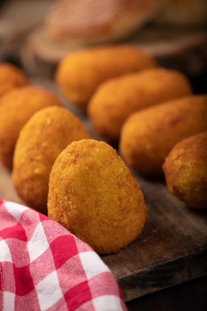 Arancini rice balls Fried rice balls in paper on brown wooden background Snack street food