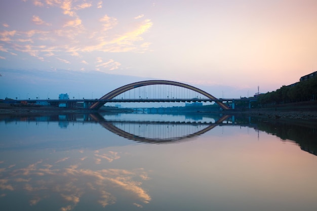 Arch highway bridge and beautiful sunset glow reflection in the river