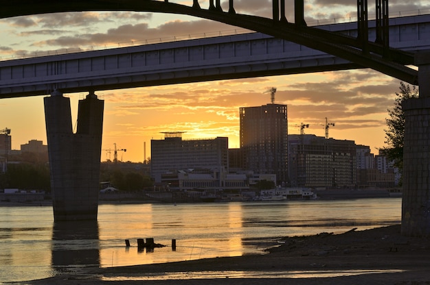 arch and metro bridge across the ob river the rising sun over the tall houses in novosibirsk