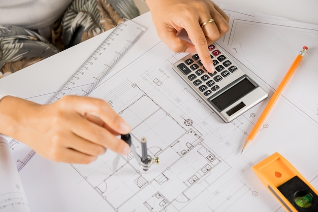 Architect drawing with divider compass on house plan blueprint paper