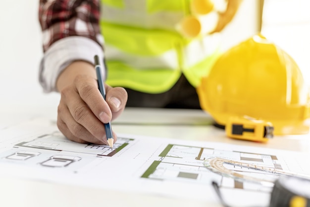 Architect engineer using a pencil to write on the blueprints he has designed, he is checking and revising the drawings before sending the work to the customers. Design and interior design ideas.