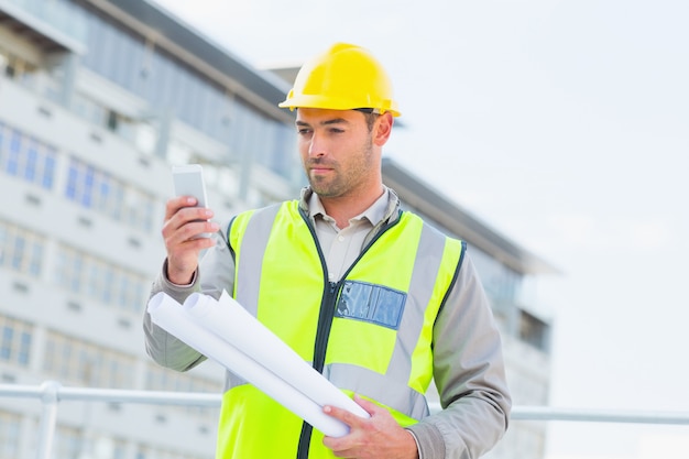 Architect using smartphone against building