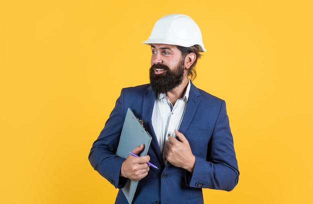 Architecture and building male builder wearing formal suit and helmet for protection working on construction project smiling man with beard wear hard hat concept of engineering