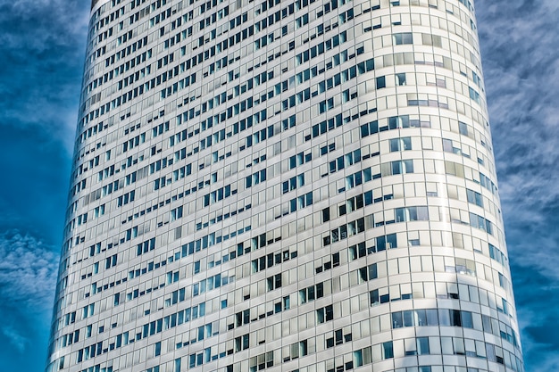 Architecture, Office skyscraper building with windows on white cladding facade with rounded walls on blue sky in La Defense, France. Business, commerce, future concept.