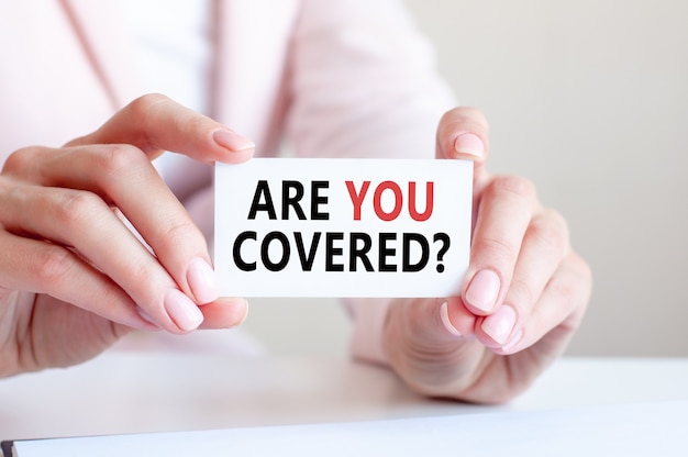 Are you covered is written on a white business card in a woman's hands.