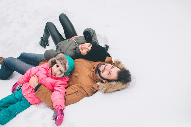 Arenthood, fashion, season and people concept - happy family with child in winter clothes outdoors