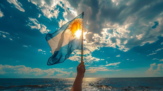 Argentina Independence Day Hand with waving country flag against blue sky with clouds