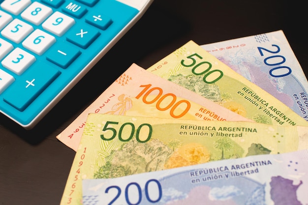 Argentine peso banknotes and a calculator in closeup photo.