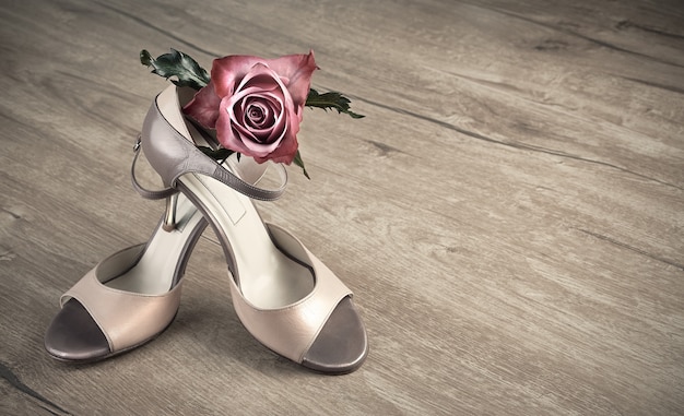 Argentine tango shoes and a rose on a wooden floor 