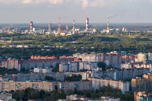 Ariel panoramic view of city and skyscrapers with a huge factory with smoking chimneys in the background