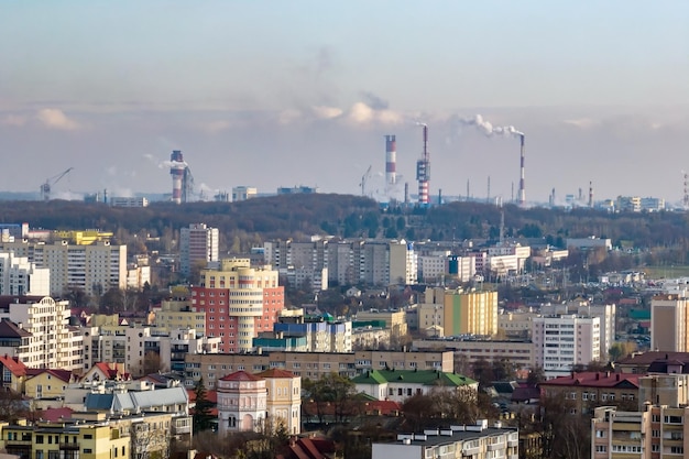 Ariel panoramic view of city with huge factory with smoking chimneys in the background