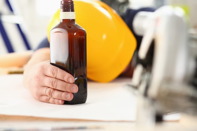 Arm of drunken worker in yellow helmet