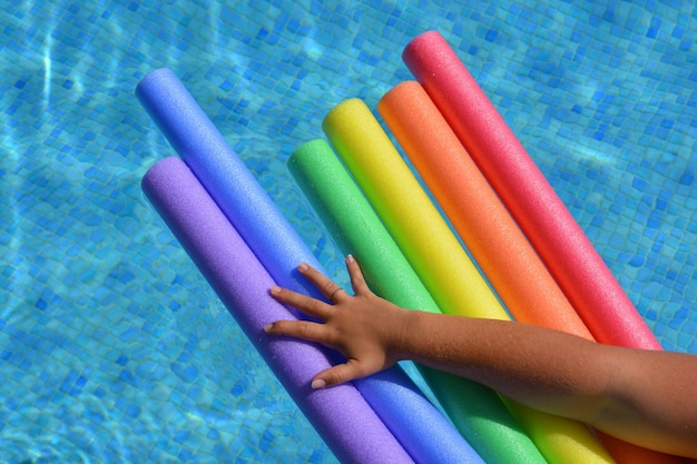 Photo arm on swimming pool noodles in rainbow colours in support of lgbtq pride