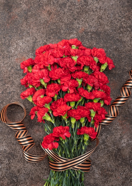 Armful carnations on dark background with ribbon