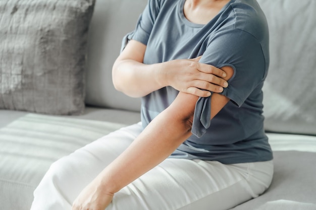 Arms Pain Woman Suffering From Painful Feeling In Arm Muscles sitting on the sofa