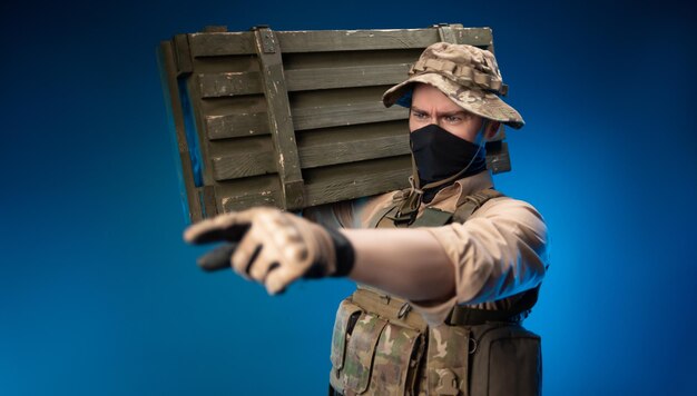 Photo an army soldier in military clothes with a box of ammunition on his shoulder