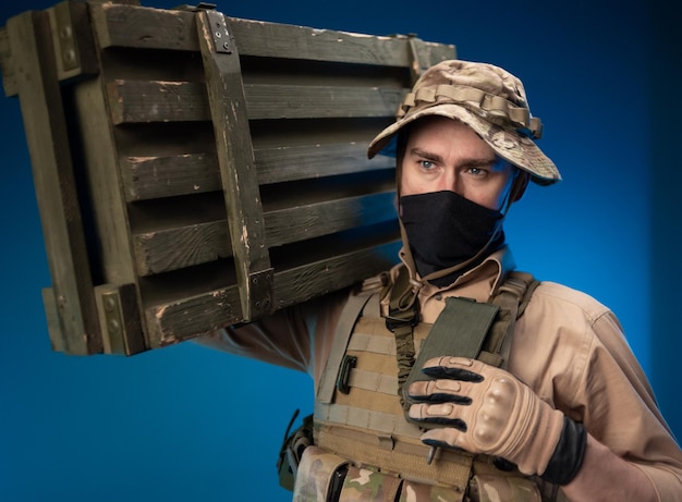 an army soldier in military clothes with a box of ammunition on his shoulder