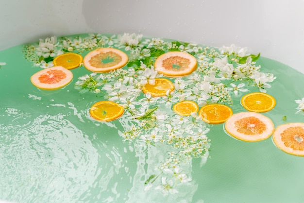 Aroma bath with flowers and oranges turquoise water Spa treatments concept