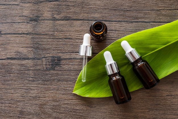 Photo aroma essential brown bottle on green leaves over the wooden table