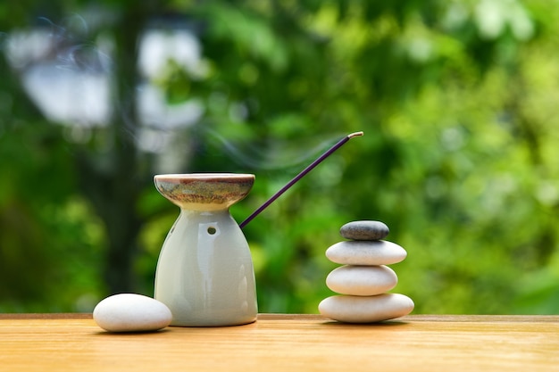 Aroma lamp with incense stick and zen stones on a wooden table