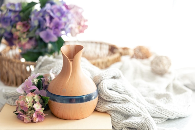 Aroma oil diffuser lamp flowers and knitted element on a blurred background