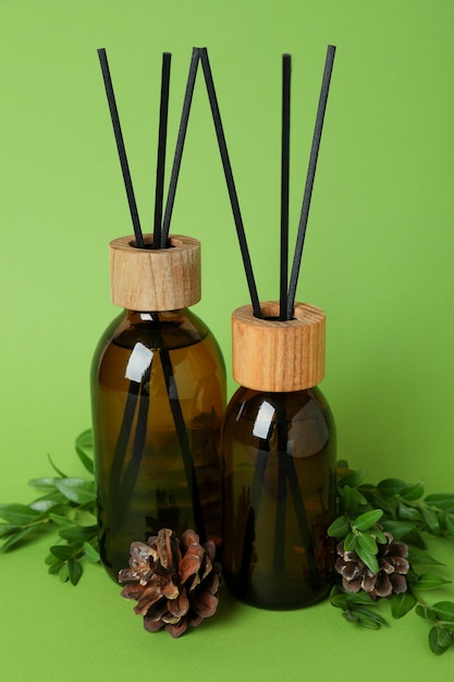 Aroma scent diffusers, cones and leaves on green background