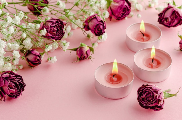 Aromatherapy concept. Three burning candles and dry roses 