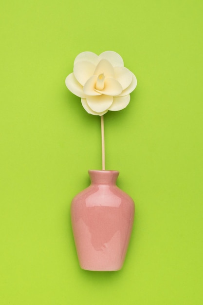 An aromatherapy vase with a wand and a large flower on a green background