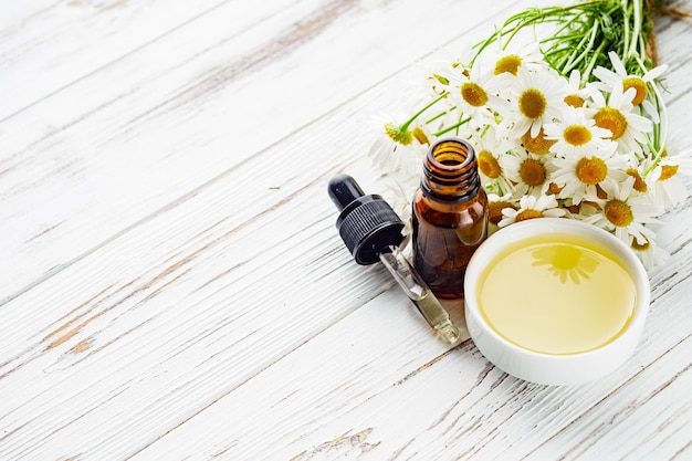 aromatic chamomile essential oil on a white wooden rustic background