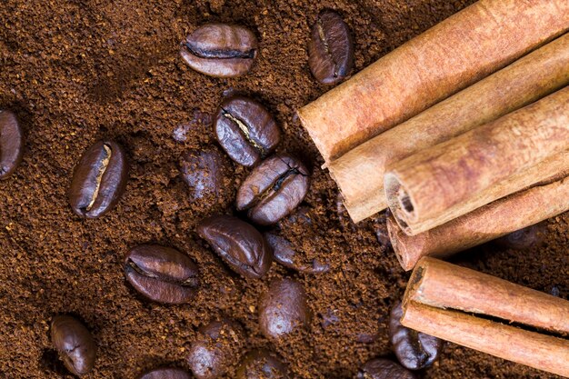 Aromatic coffee and cinnamon on ground coffee powder, whole cinnamon sticks and coffee beans and ground powder, closeup