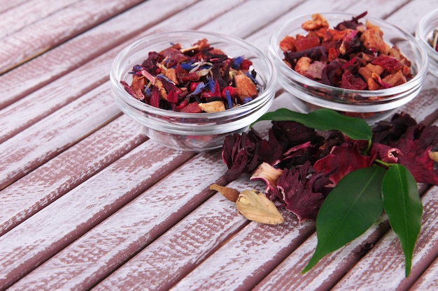 Aromatic dry tea in bowls on wooden background