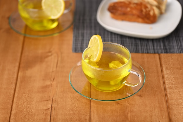 Aromatic lemon tea in a glass cup on the wooden table.