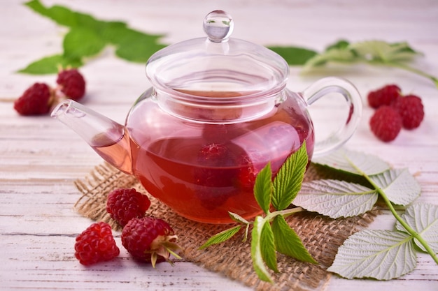 Aromatic raspberry tea in a glass teapot on a white background