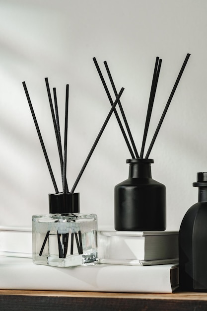 Aromatic reed diffuser on white books with shadows playing on the wall