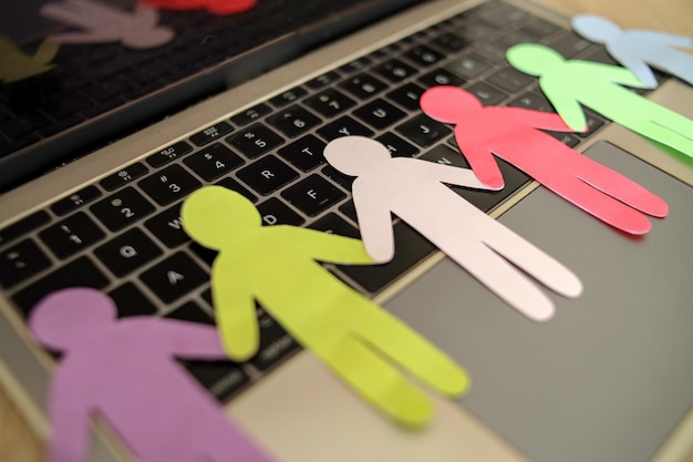 Photo arrangement of different color paper human figures on laptop diversity and inclusion concept