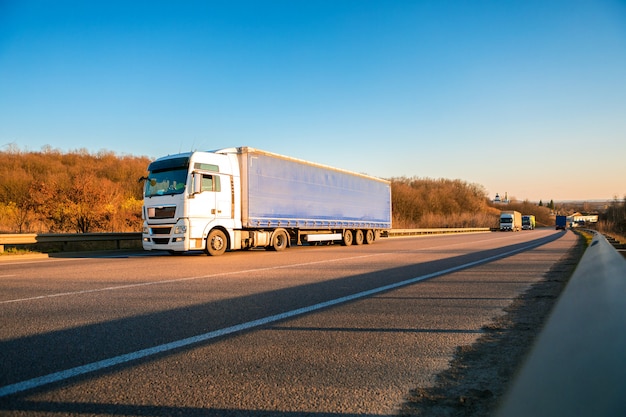 Arriving white truck on the road in a rural landscape at sunset