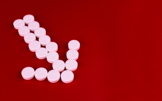 Arrow made of white pills on a red background Copy space