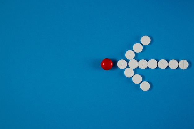 Arrow of pills indicates a red pill on blue table from above