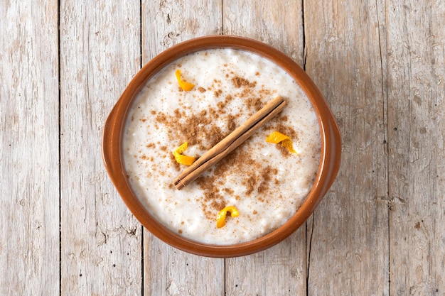 Arroz con leche Rice pudding with cinnamon in clay bowl on wooden table