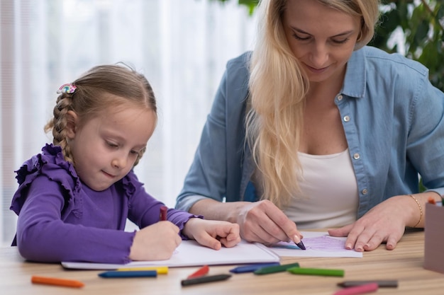 Art class for child creative hobby Teacher helping Pre School Pupil little taleted girl drawing