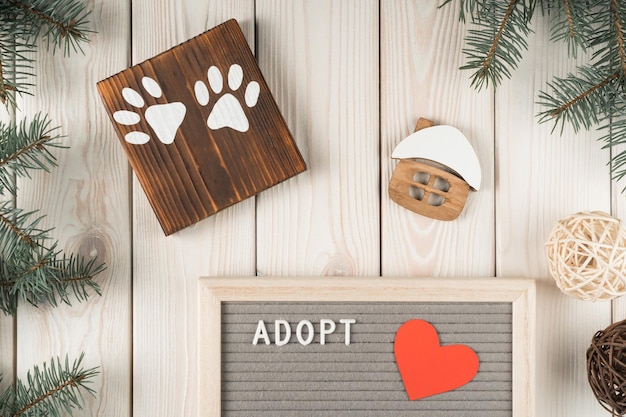 Photo art creative composition of wooden board with two animal paws house model and adopt board with fir tree twig decoration