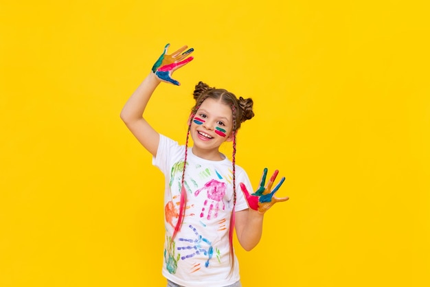 Art drawing for children A little girl on a yellow background with her hands stained in paint