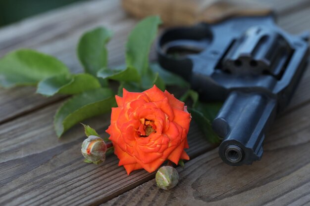 art photo. vintage still life with gun and rose on wooden background