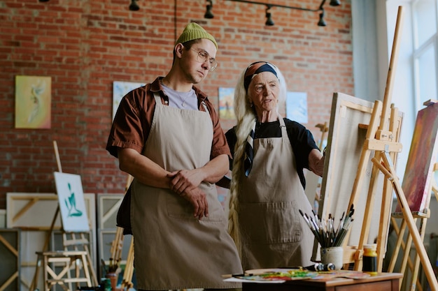 Photo art teacher working with young man during painting class