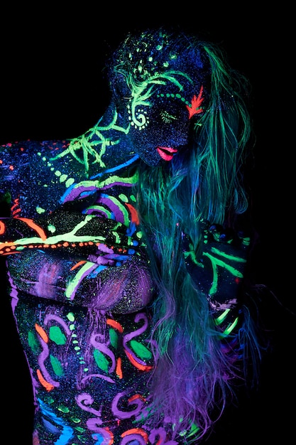 Art woman body art on the body dancing in ultraviolet light. Bright abstract drawings on the girl body neon color