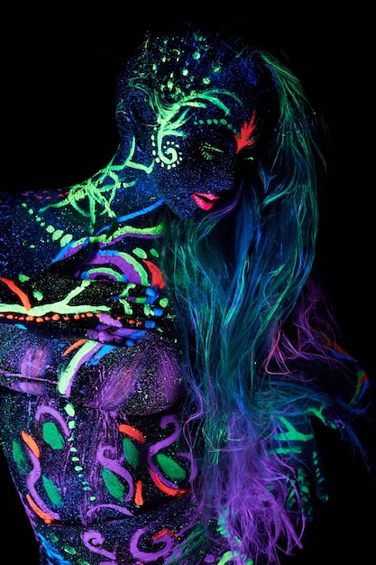 Art woman body art on the body dancing in ultraviolet light. Bright abstract drawings on the girl body neon color