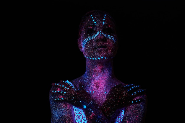 Art woman cosmos in ultraviolet light. Entire body is covered with colored droplets