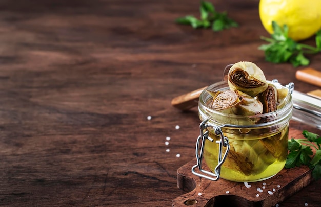 Artichokes in olive oil glass jar rustic wooden table still life copy space selective focus