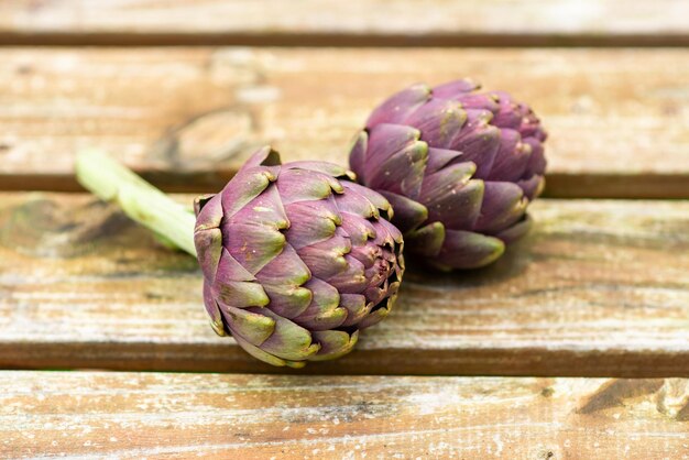 Artichokes on a wooden background closeup Two purple artichokes